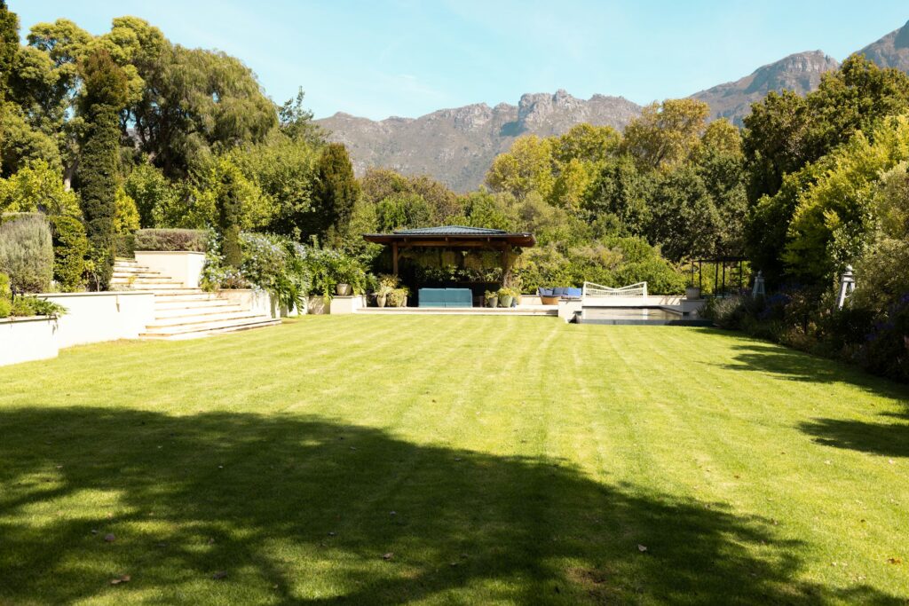 Lush green lawn stretches towards gazebo with mountains in background at home