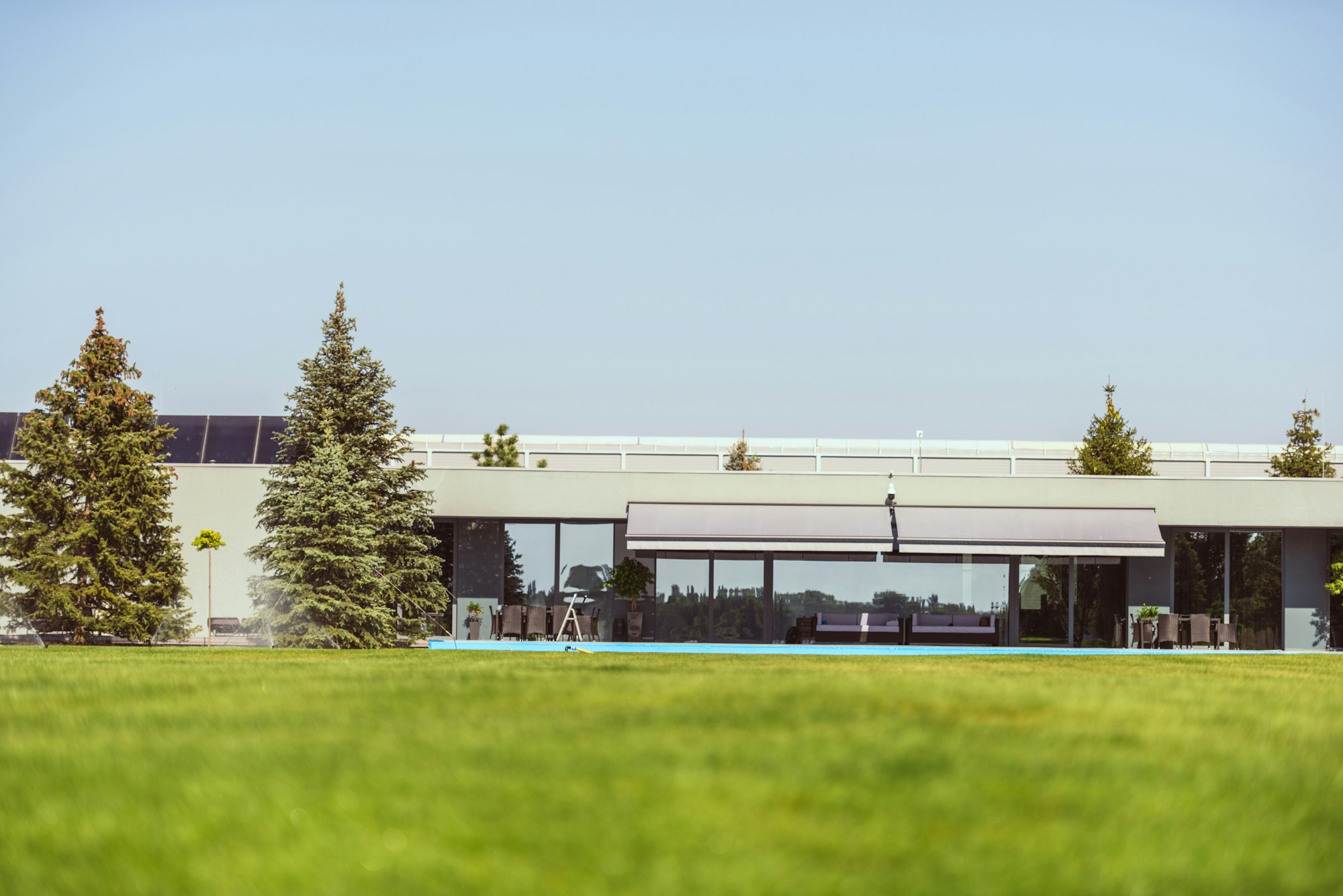 surface level of green lawn and modern cottage under blue clear sky