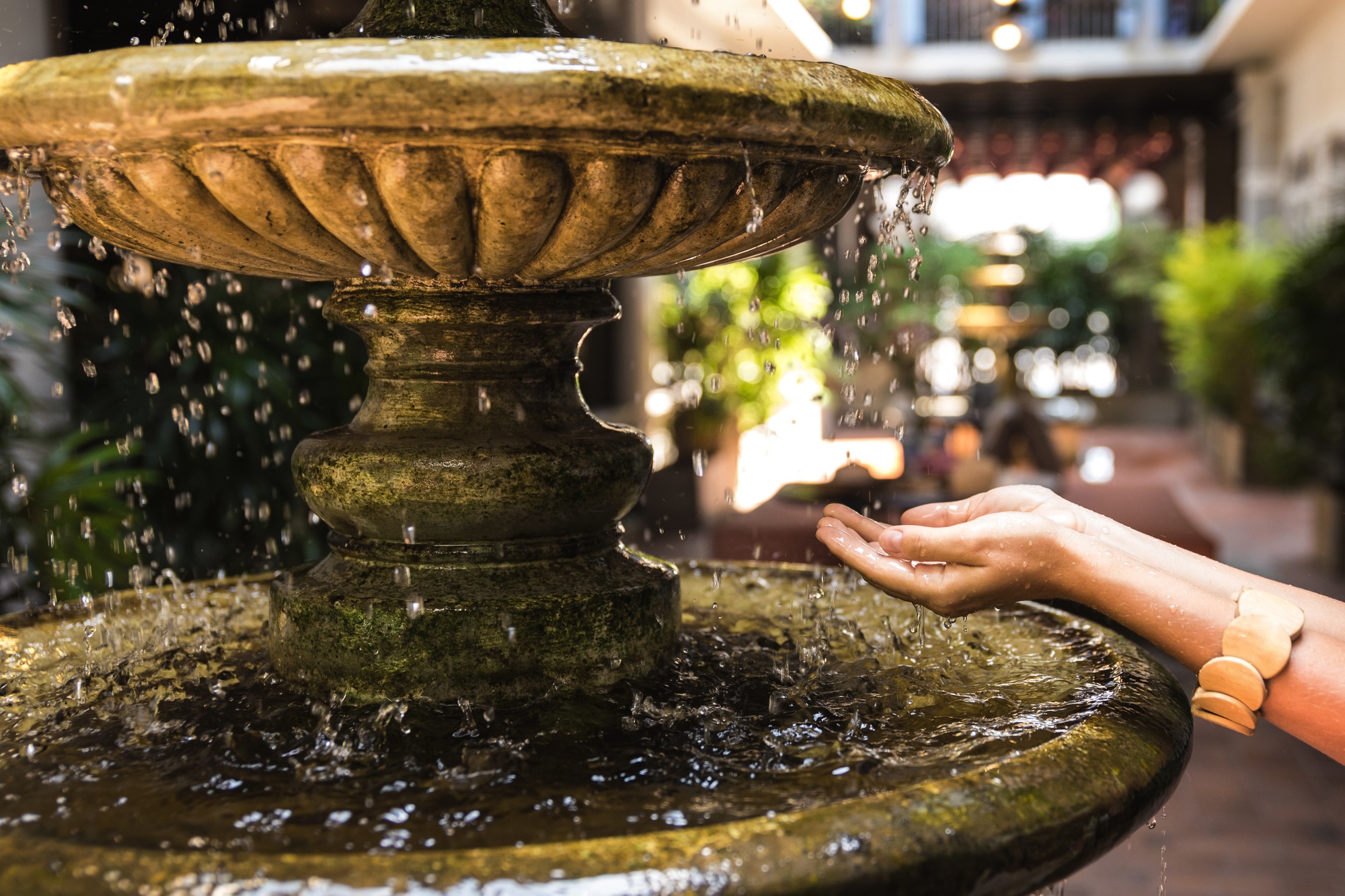 Female hands ancient fountain with splashing water drops